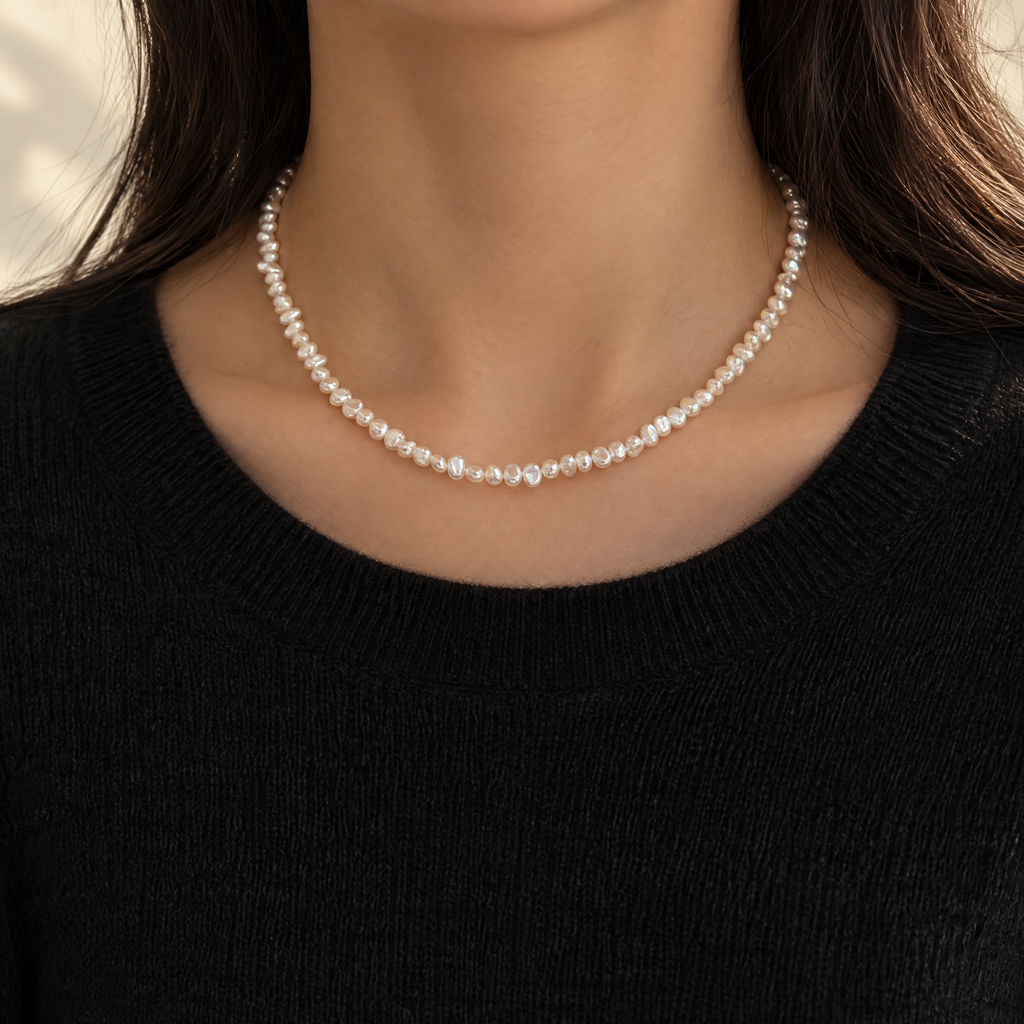 Dainty baroque pearl necklace worn with a black knit sweater