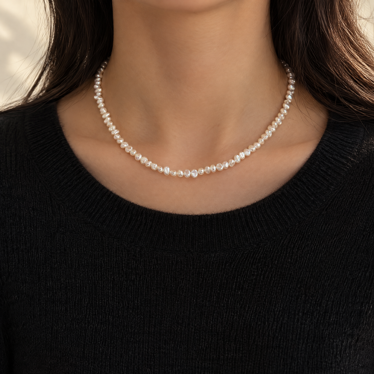 Dainty baroque pearl necklace worn with a black knit sweater